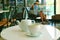 Cup of hot green tea with teapot on the white cafe`s round table