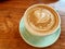 A cup of hot latte art heart variation coffee on wooden background