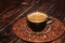 Cup of hot latte coffee on a dark wooden table with grains, selective focus.