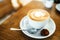 Cup with hot tasty coffee on wooden table in cafe, close up