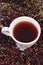 Cup of hot tea with elderberry juice and heap of berry, healthy nutrition