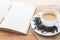 Cup of hot tea on sackcloth with dried tea leaves and handmade book on wooden table with copy space