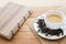 Cup of hot tea on sackcloth with dried tea leaves and handmade book on wooden table with copy space from high angle view.