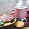 A cup of hot tea stands on a wooden table next to a wooden plate on which are gingerbread cookies made from orange slices against