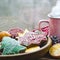 A cup of hot tea stands on a wooden table next to a wooden plate on which are gingerbread cookies made from orange slices against