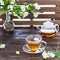 Cup of jasmine tea and transparent tea pot on the wooden table. Spring tea party. Copy space
