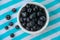 A Cup Of Juicy Blueberries At A Bright Blue Stripy Background