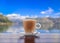 Cup of latte coffee with a blurred view of Kotor Bay or Boka Kotorska in background in Montenegro, on the Adriatic Sea