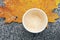 Cup with leftover cappuccino coffee and yellow autumn maple leaves on marble background, copy space