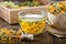 Cup of marigold tea and paper bag of dry calendula flowers. Medicinal herbs in wooden crate on background.