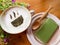 Cup of matcha green tea latte art with green tea snack on wooden