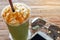 Cup of the matcha greentea frappe with caramel whipped cream on the brown bark beautiful texture background with warm light