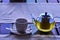 A cup of morning green tea. A transparent teapot with freshly brewed green tea and a white porcelain cup on the table by the windo