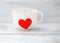 Cup red goroshnek and red heart on a string on a wooden white ba