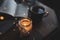 Cup of resh balck coffee with open paper book and burning candle at background over glow lights close up.