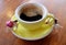 Cup of smiling shape black coffee with two cute mini, cupid girl figurine on wooden table