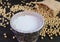 Cup of Soy Milk Isolated on the Table with Blurry Soybeans Scattered from Burlap Bag