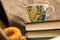 A cup of strong tea on a saucer, donuts on a plate and a stack of books on the table