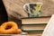 A cup of strong tea on a saucer, donuts on a plate and a stack of books on the table