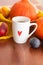 Cup of tea with an autumn decor of pumpkins, plums, textiles and peaches on a wooden background