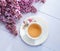 Cup of tea and branches of blooming lilac on wooden table