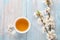 Cup of tea and branches of blossoming apricot on old wooden shabby background