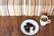 Cup of tea and chocolate candies on white plate, stack of old book on wooden table, education concept background, many books piles