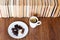 Cup of tea and chocolate candies on white plate, stack of old book on wooden table, education concept background, many books piles