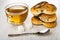 Cup with tea, cookies with poppy seeds, spoon, sugar cubes on wooden table