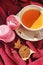 A cup of tea with cookies. Sweet and colorful fresh macaroons on a red background. Delicious and beautiful desserts for tea