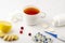 Cup of tea with cranberries, ginger, lemon and pills on white, close up. The concept of seasonal diseases and treatment of colds,