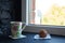 A cup with tea and cupcake near the window