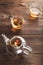 A cup of tea with fresh leaves of green and black tea on a textural dark wooden background with copy space. Flower tea in a glass