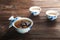 A cup of tea with fresh leaves of green and black tea on a textural dark wooden background with copy space. Tea flower in a porcel