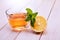 Cup of tea, glass teapot, mint and lemon on a wooden table