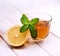 Cup of tea, glass teapot, mint and lemon on wooden table