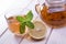 Cup of tea, glass teapot, mint and lemon on wooden table