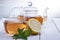 Cup of tea, glass teapot, mint and lemon on wooden table