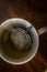 Cup of Tea with infuser in hot smoky water with green tea, mint herbs and honey on a dark wooden background