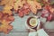 Cup of tea with lemon in hand, colorful autumn leaves on wooden board. Fall still life. Top view. Matte effect.