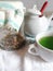 Cup of tea from natural herbs,a cup of green tea, a bowl of sugar and Grandma`s jars with natural herbs, flowers and roots dried a