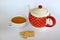 Cup of tea next to a dotted teapot and three cookies isolated on white background