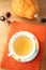 A cup of tea on orange knitted mat and pumpkin on wood table