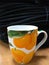A cup of tea with orange oranges and green leaves on a dark background.