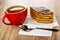 Cup of tea, piece of cake, spoon on paper napkin on wooden table