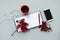 Cup of tea with red leaves of girlish wild grape, open empty note pad, smartphone and headphones on gray wooden background. Top