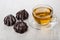 Cup of tea on saucer, glazed chocolate marshmallow on table