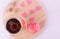 A cup of tea and a saucer with strawberry cookies along with sugar hearts and pink hearts on a light round wooden tray