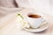 Cup of tea on a saucer and a white freesia flower