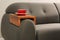 Cup of tea on sofa with wooden armrest table in room. Interior element